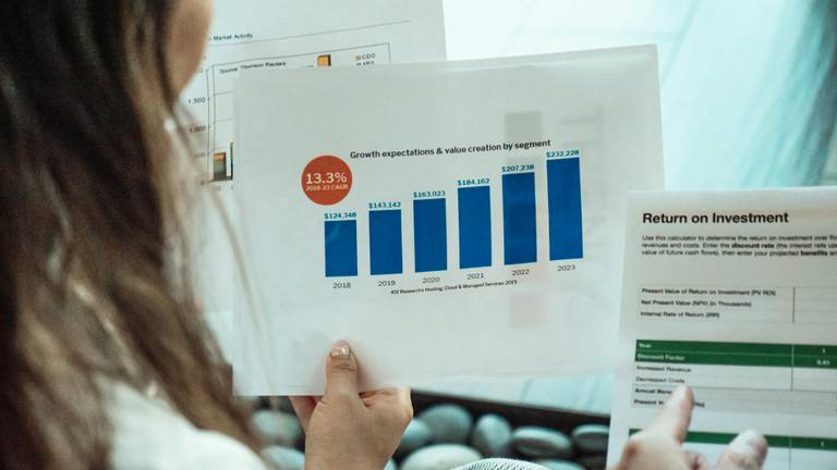 ROI Report for Remote Marketing Pro Success Person analyzes an ROI report and a bar chart showing growth expectations and value creation for a business.